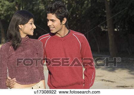 Stock Image - Close-up of a young couple walking in a park. Fotosearch