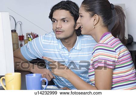 Stock Photo - Close-up of a young man and a young woman working on a computer in the office. Fotosearch