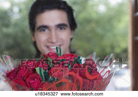 Close-up of a young man hiding behind a bouquet of flowers View Large Photo Image Stock Photo - Close-up of a young man hiding behind a bouquet of flowers. Fotosearch