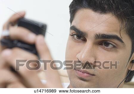 Close-up of a young man holding a mobile phone View Large Photo Image Stock Photo - Close-up of a young man holding a mobile phone. Fotosearch