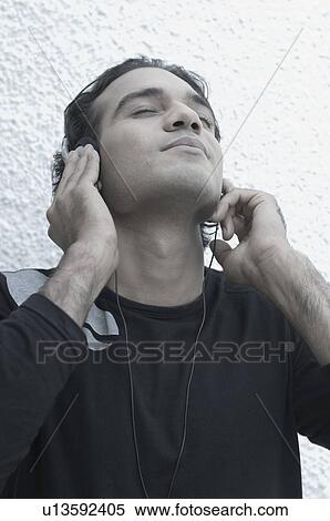 Close-up of a young man listening to music View Large Photo Image Stock Photography - Close-up of a young man listening to music. Fotosearch