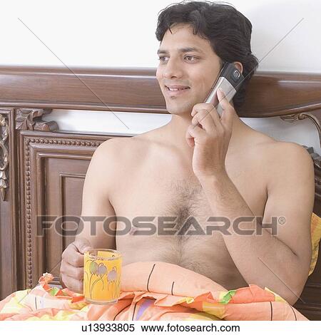 Close-up of a young man talking on a mobile phone and holding a cup of coffee View Large Photo Image Stock Photography - Close-up of a young man talking on a mobile phone and holding a cup of coffee. Fotosearch