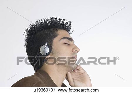 Close-up of a young man wearing headphones and listening to music View Large Photo Image Stock Photo - Close-up of a young man wearing headphones and listening to music. Fotosearch