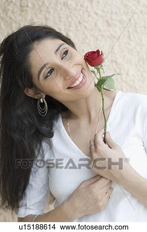 Close-up of a young woman holding a rose View Large Photo Image Picture - Close-up of a young woman holding a rose. Fotosearch