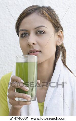 Close-up of a young woman holding a glass of juice View Large Photo Image Stock Image - Close-up of a young woman holding a glass of juice. Fotosearch