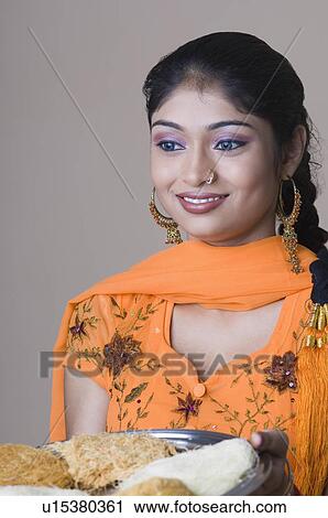 Close-up of a young woman holding a plate of traditional sweets and smiling View Large Photo Image Stock Image - Close-up of a young woman holding a plate of traditional sweets and smiling. Fotosearch