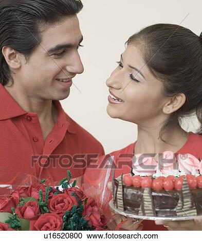 Close-up of a young woman holding a chocolate cake and looking at a young man View Large Photo Image Stock Image - Close-up of a young woman holding a chocolate cake and looking at a young man. Fotosearch