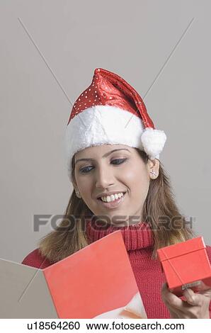 Close-up of a young woman holding a gift and reading a greeting card View Large Photo Image Stock Image - Close-up of a young woman holding a gift and reading a greeting card. Fotosearch