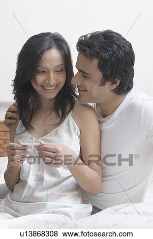Close-up of a young woman holding a home pregnancy test and smiling with a young man beside her View Large Photo Image Stock Photo - Close-up of a young woman holding a home pregnancy test and smiling with a young man beside her. Fotosearch