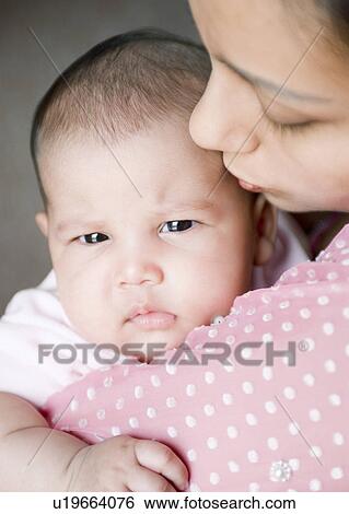 Close-up of a young woman kissing her daughter View Large Photo Image Stock Photograph - Close-up of a young woman kissing her daughter. Fotosearch