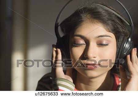 Stock Image - Close-up of a young woman listening to music. Fotosearch