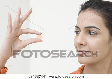 Stock Image - Close-up of a young woman taking a pill. Fotosearch