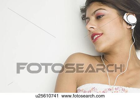 Close-up of a young woman wearing headphones and listening to music View Large Photo Image Stock Image - Close-up of a young woman wearing headphones and listening to music. Fotosearch