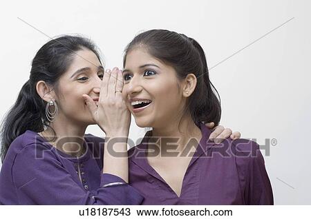 Close-up of a young woman whispering into another young woman's ear View Large Photo Image Stock Image - Close-up of a young woman whispering into another young woman's ear. Fotosearch