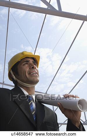 Close-up of an architect holding blueprints at a construction site View Large Photo Image Stock Photo - Close-up of an architect holding blueprints at a construction site. Fotosearch