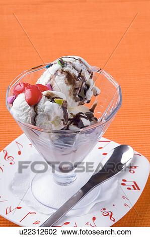 Stock Image - Close-up of an ice-cream sundae with a spoon on a plate. Fotosearch