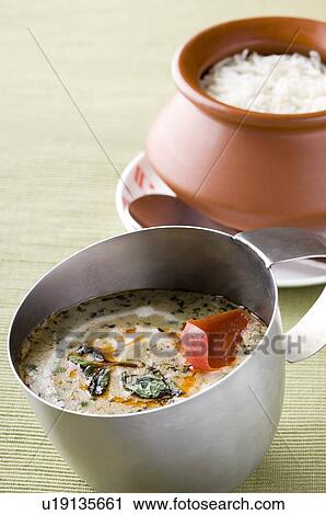 Stock Image - Close-up of curry in a mug with a bowl of rice on a plate. Fotosearch
