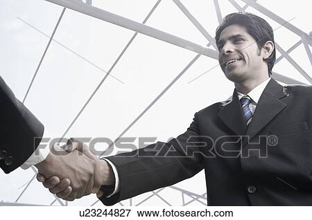 Stock Photo - Close-up of two businessmen shaking hands at the construction site. Fotosearch