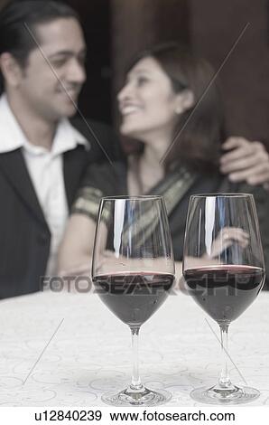 Close-up of two wine glasses with a mid adult man and a young woman smiling in the background View Large Photo Image Stock Photo - Close-up of two wine glasses with a mid adult man and a young woman smiling in the background. Fotosearch