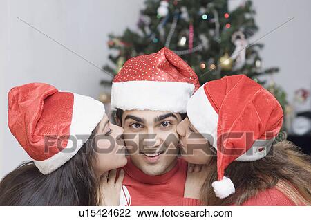 Close-up of two young women kissing a young man on the cheeks View Large Photo Image Stock Image - Close-up of two young women kissing a young man on the cheeks. Fotosearch