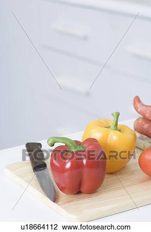 Stock Image - Close-up of vegetables and a knife on a cutting board in a kitchen. Fotosearch