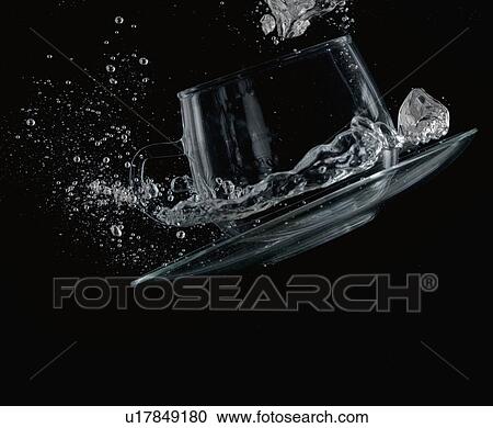 Stock Image - Close-up of water splashing out of a cup. Fotosearch
