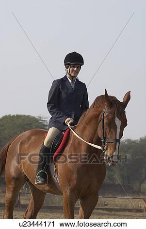 Stock Image - Female jockey riding a horse. Fotosearch