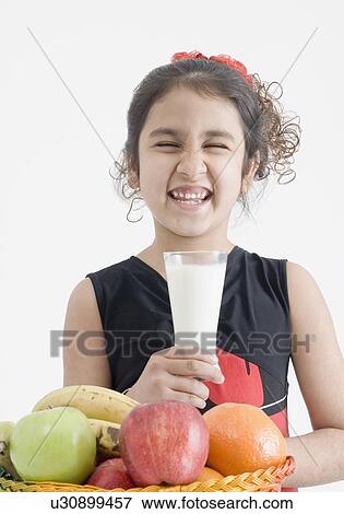 Girl holding a glass of milk and making a face View Large Photo Image Stock Photo - Girl holding a glass of milk and making a face. Fotosearch