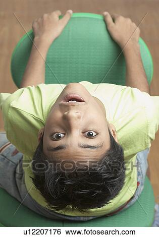 Stock Photograph - High angle view of a boy sitting on a chair. Fotosearch