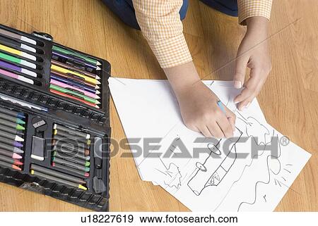 Stock Photo - High angle view of a child's hand drawing a picture on a sheet of paper. Fotosearch