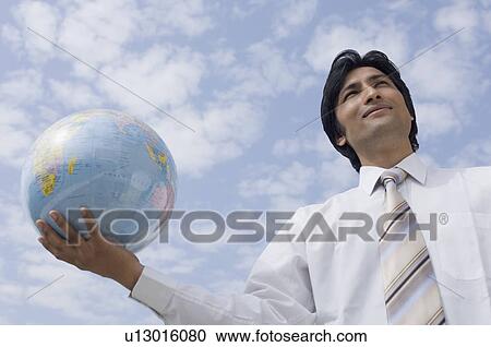 Low angle view of a businessman holding a globe View Large Photo Image Stock Image - Low angle view of a businessman holding a globe. Fotosearch