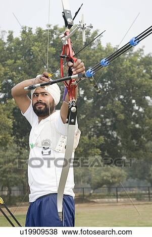 Low angle view of a young man aiming with a bow and arrow View Large Photo Image Stock Photo - Low angle view of a young man aiming with a bow and arrow. Fotosearch