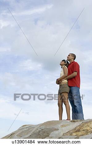 Low angle view of a young man embracing a mid adult woman from behind View Large Photo Image Picture - Low angle view of a young man embracing a mid adult woman from behind. Fotosearch
