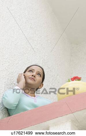 Low angle view of a young woman leaning against a wall View Large Photo Image Stock Photo - Low angle view of a young woman leaning against a wall. Fotosearch