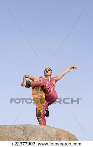Low angle view of a young woman performing Bharatnatyam on a rock View Large Photo Image Stock Image - Low angle view of a young woman performing Bharatnatyam on a rock. Fotosearch