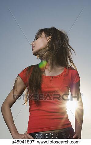 Low angle view of a young woman standing with arms akimbo View Large Photo Image Stock Photo - Low angle view of a young woman standing with arms akimbo. Fotosearch