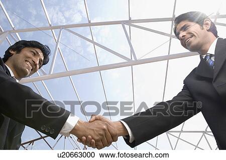 Low angle view of two architects shaking hands View Large Photo Image Stock Image - Low angle view of two architects shaking hands. Fotosearch