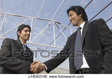 Low angle view of two architects shaking hands View Large Photo Image Stock Photograph - Low angle view of two architects shaking hands. Fotosearch