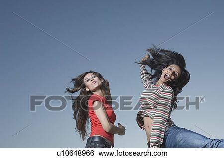 Low angle view of two young women jumping View Large Photo Image Stock Photograph - Low angle view of two young women jumping. Fotosearch