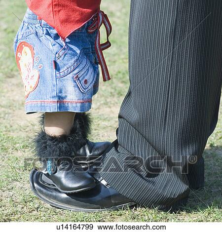 Stock Photo - Low section view of a baby girl standing on her father's feet. Fotosearch
