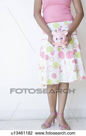 Low section view of a woman holding a piggy bank View Large Photo Image Stock Image - Low section view of a woman holding a piggy bank. Fotosearch