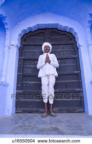 Picture - Mature man standing at a doorway with his folded hands, Pushkar, Rajasthan, India. Fotosearch