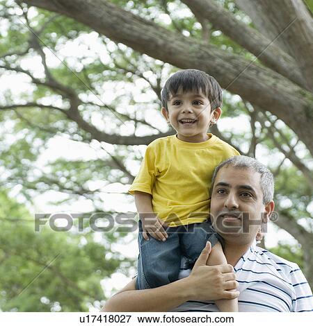 Mid adult man carrying his son on his shoulders View Large Photo Image Stock Photo - Mid adult man carrying his son on his shoulders. Fotosearch