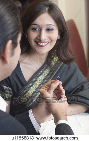 Stock Photo - Mid adult man giving a ring to a young woman. Fotosearch