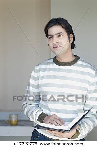 Mid adult man holding a diary View Large Photo Image Stock Photography - Mid adult man holding a diary. Fotosearch