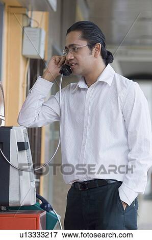 Mid adult man talking on a pay phone View Large Photo Image Stock Photo - Mid adult man talking on a pay phone. Fotosearch