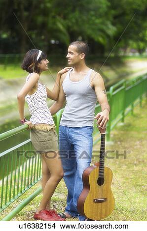 Picture - Mid adult woman and a young man looking at each other and smiling. Fotosearch