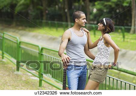 Stock Photograph - Mid adult woman and a young man looking at each other and smiling. Fotosearch