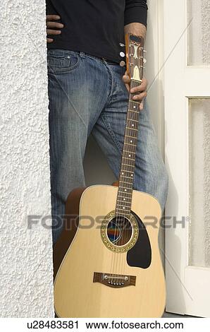 Mid section view of a man holding a guitar in a doorway View Large Photo Image Stock Image - Mid section view of a man holding a guitar in a doorway. Fotosearch
