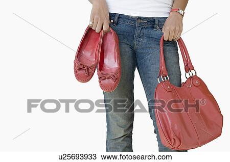 Mid section view of a woman holding a hand bag and a pair of shoes View Large Photo Image Stock Image - Mid section view of a woman holding a hand bag and a pair of shoes. Fotosearch